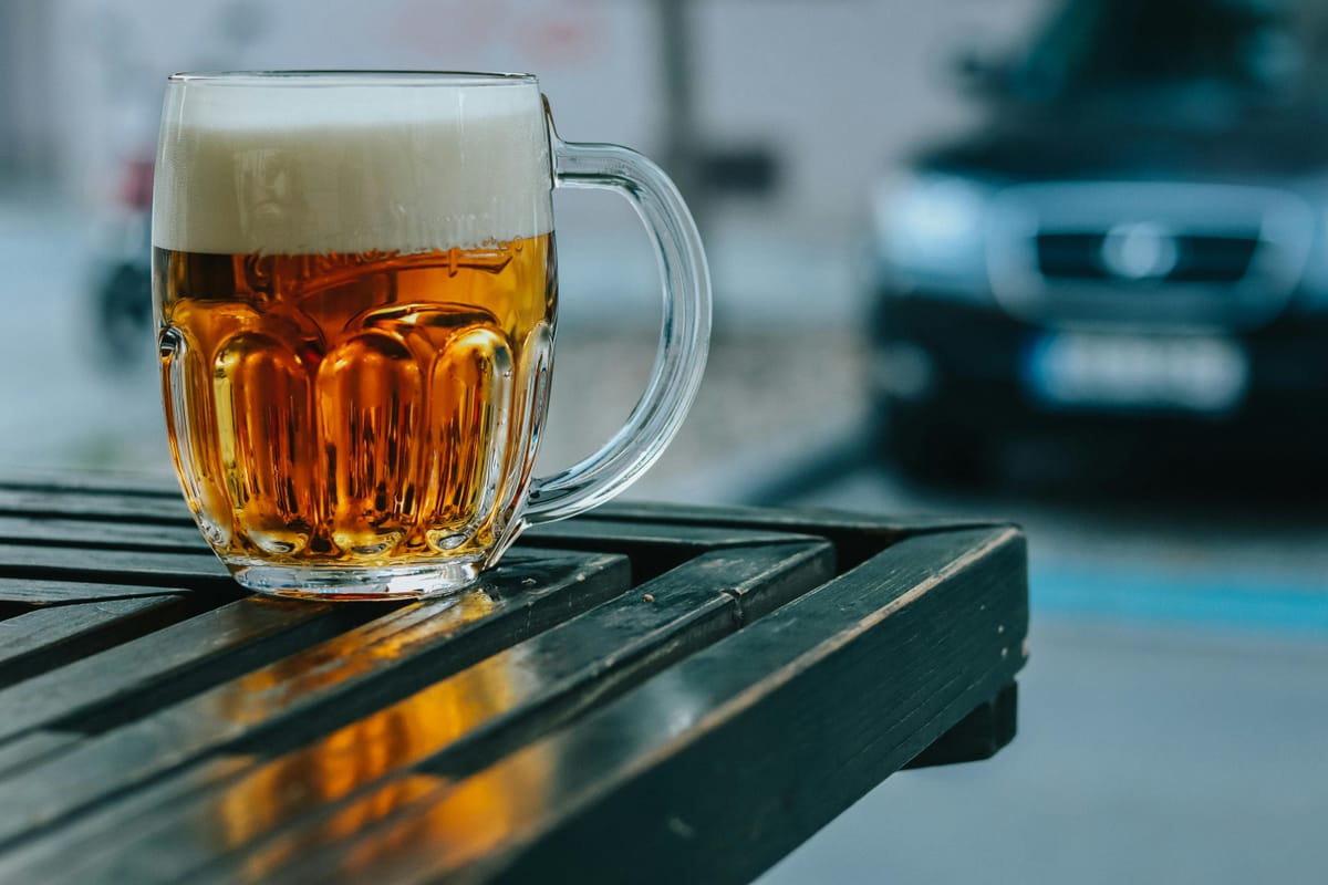 A pint of beer with foam on a wooden table.