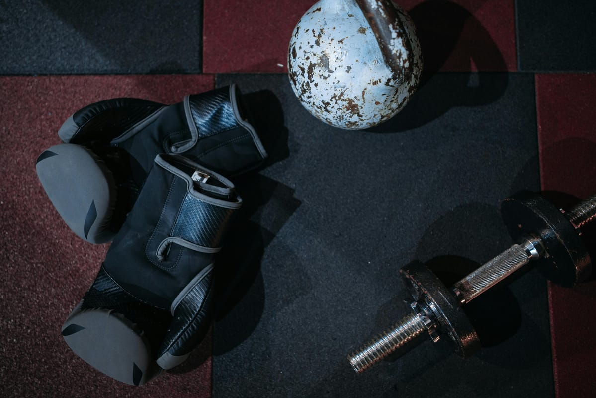 A kettlebell and dumbbells on a wooden gym floor.