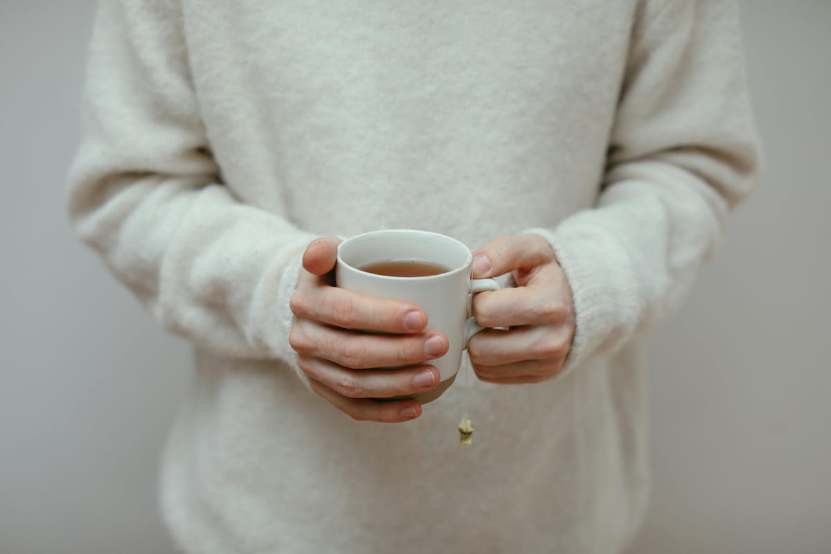 Hands holding a tea cup in soft natural light.
