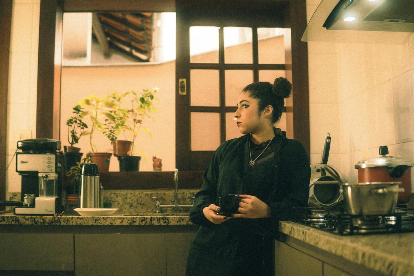 A quiet kitchen at dawn with a window showing soft early light and a single coffee cup on the counter.