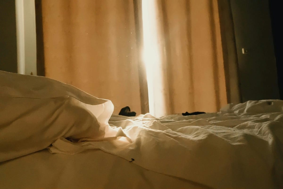 A simple bedroom with soft morning light through a window.