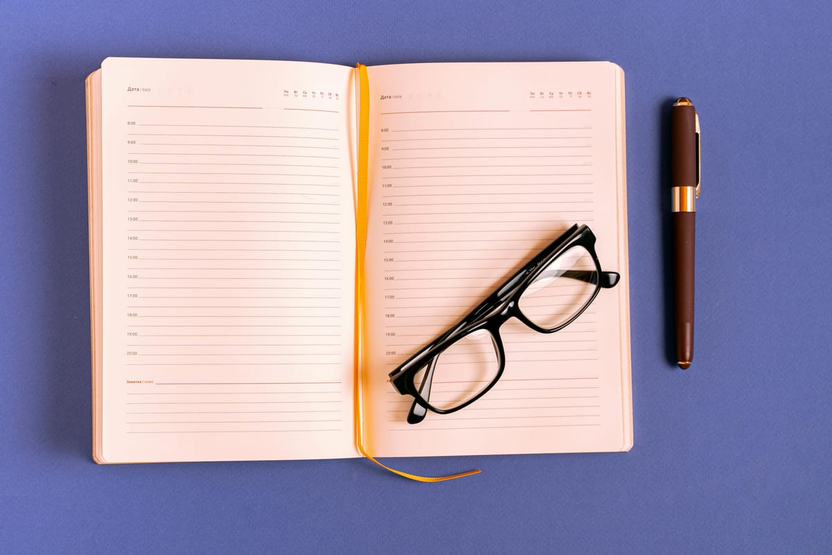 A simple clinical desk with reading glasses and an open notebook.