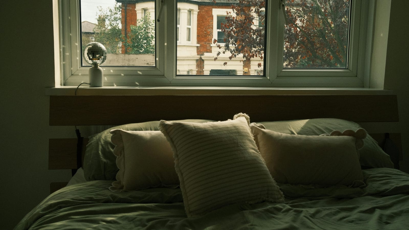 An unmade bed in a quiet bedroom with morning light through a window.