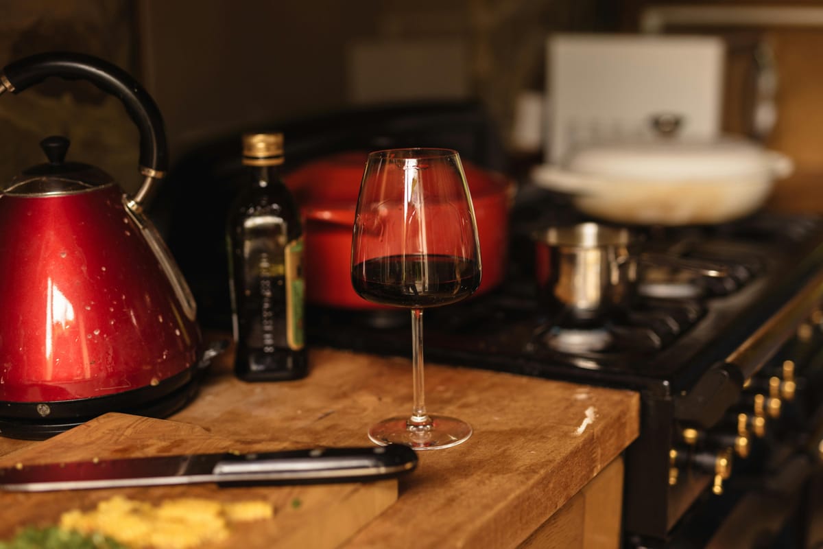 A wine glass on a kitchen counter in evening light.