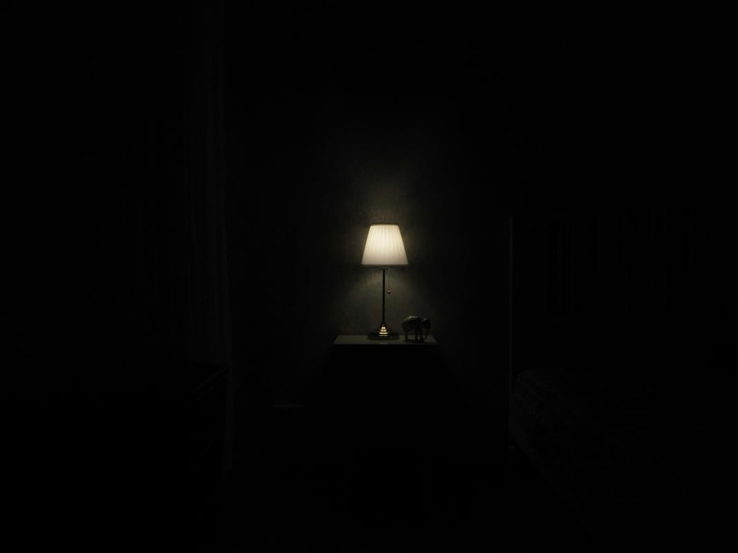 A glass of water on a bedside table in dim light.