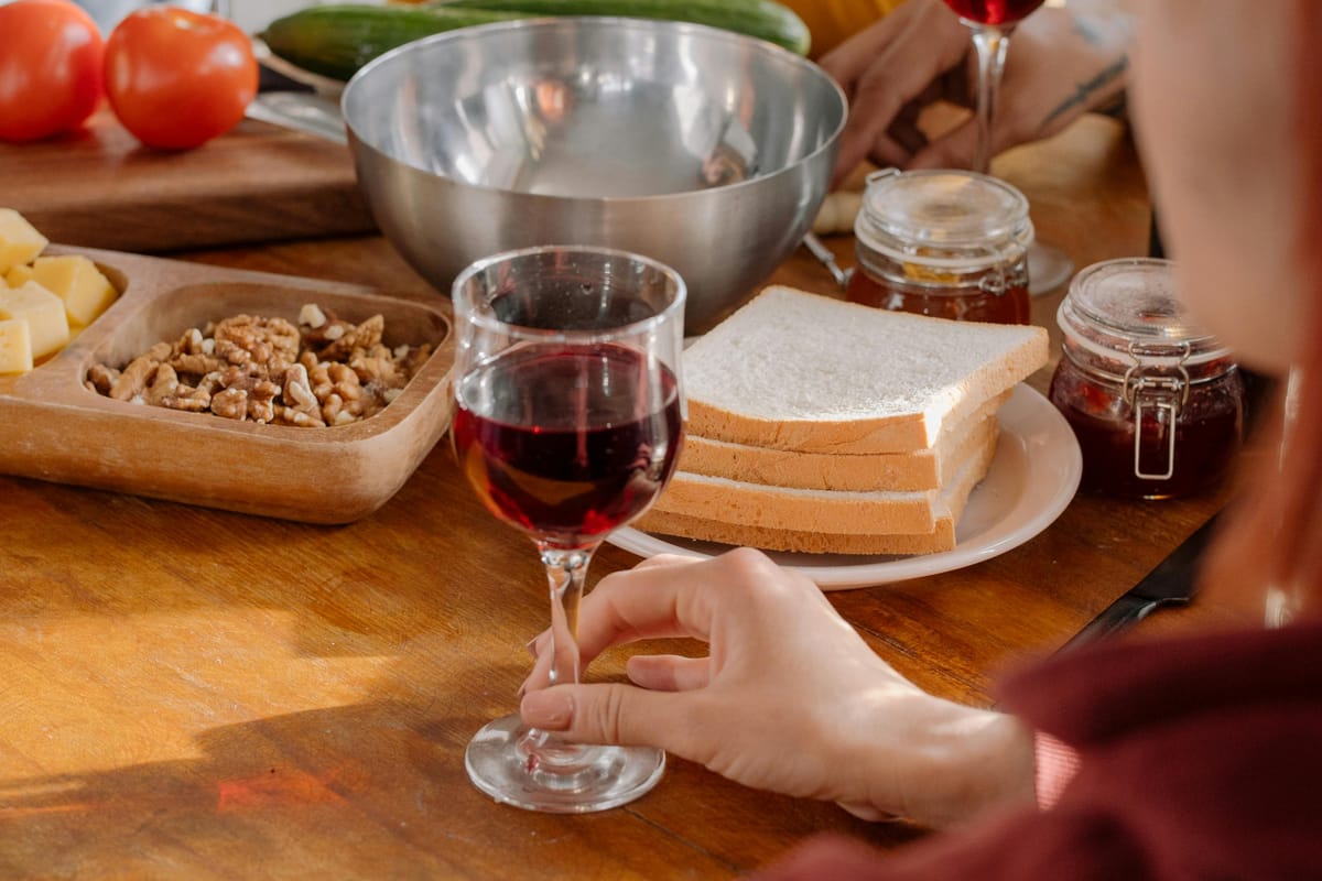 Fresh vegetables and a glass of wine on a wooden kitchen table.