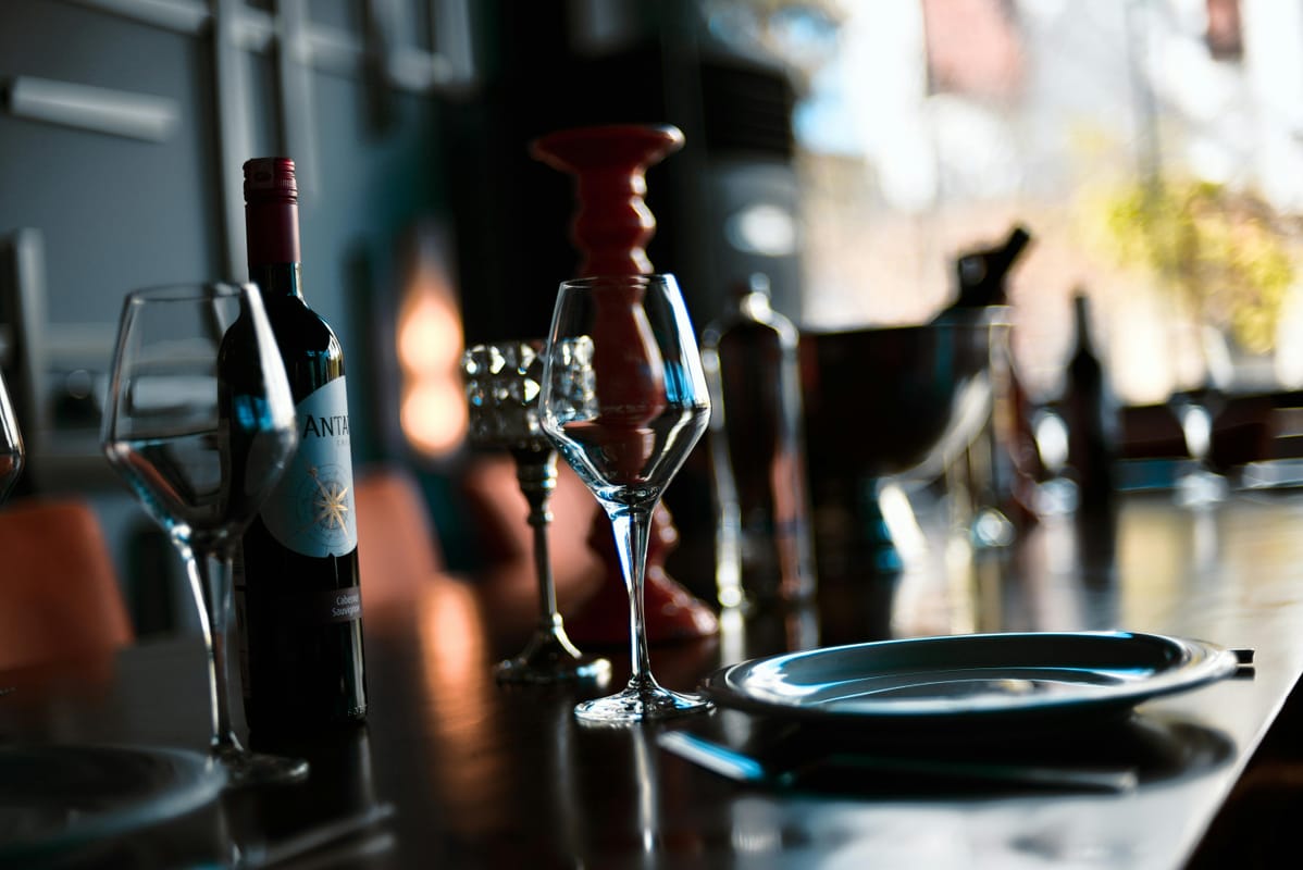 An empty plate beside an empty wine glass on a restaurant table.