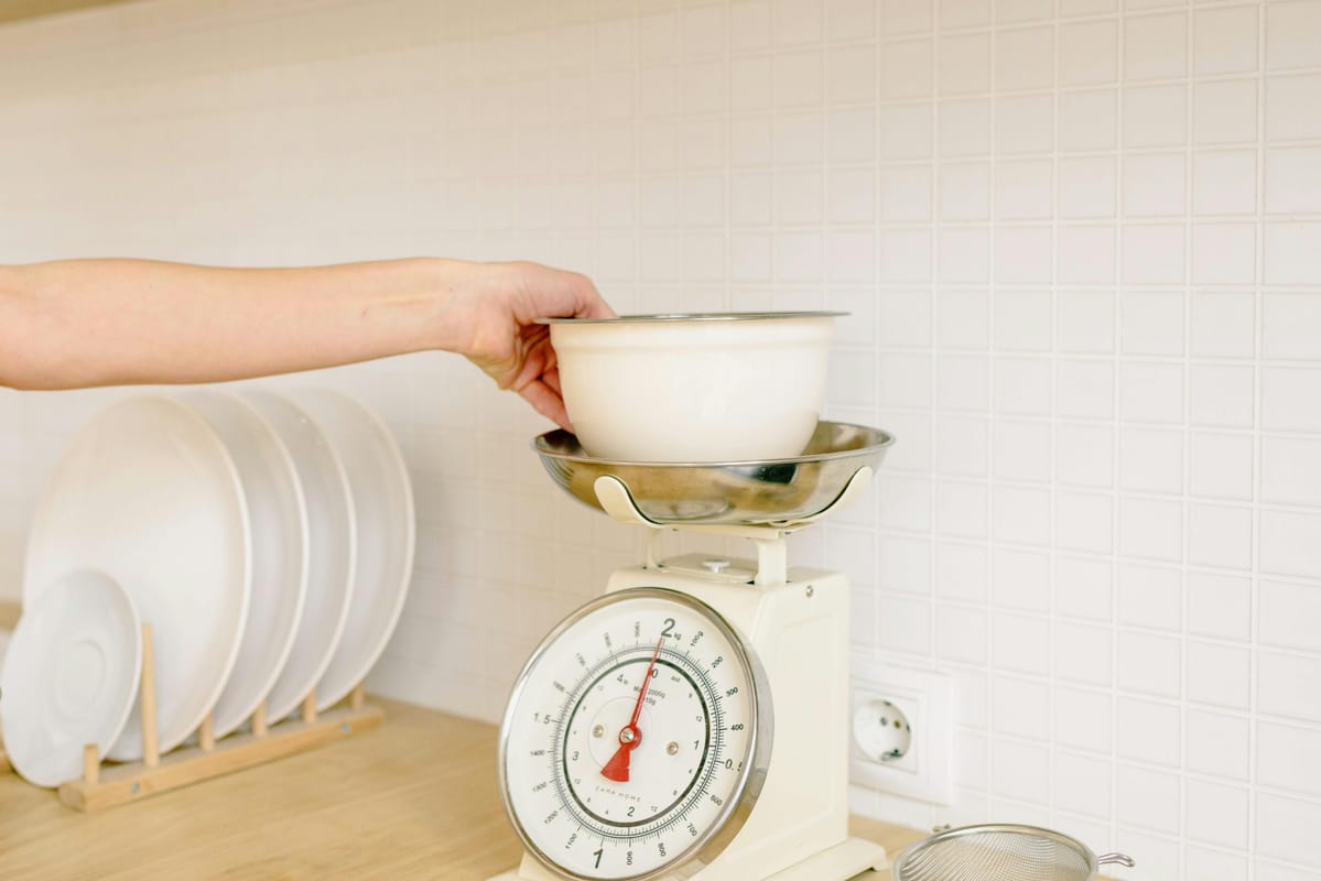 A kitchen scale with a small measure on a wooden surface.