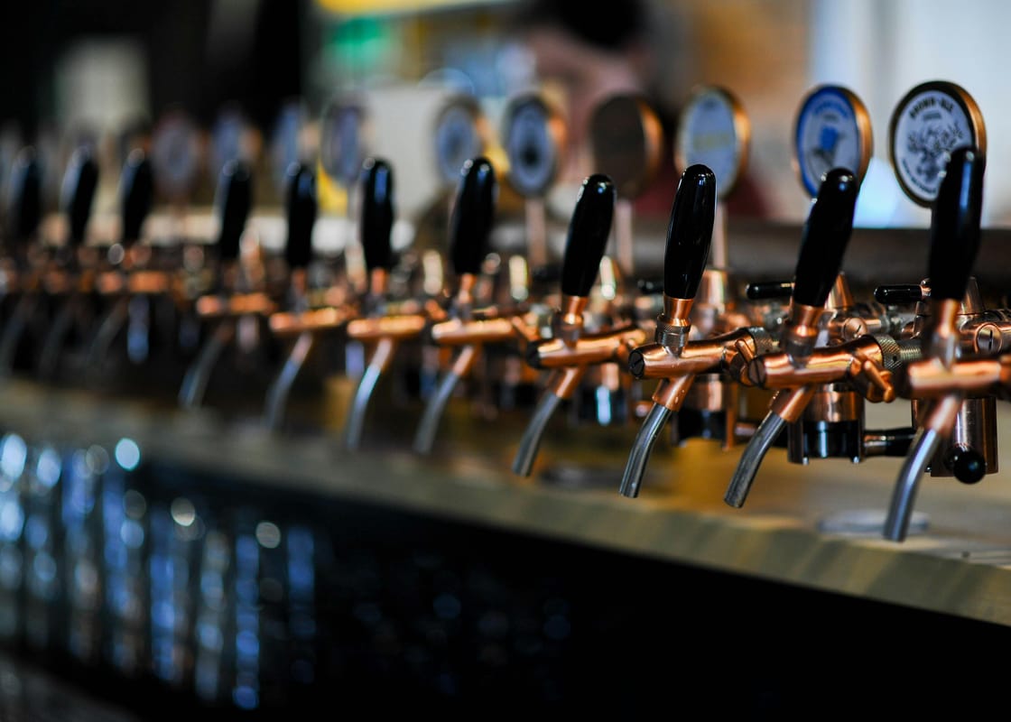 A row of pints lined up on a wooden bar.