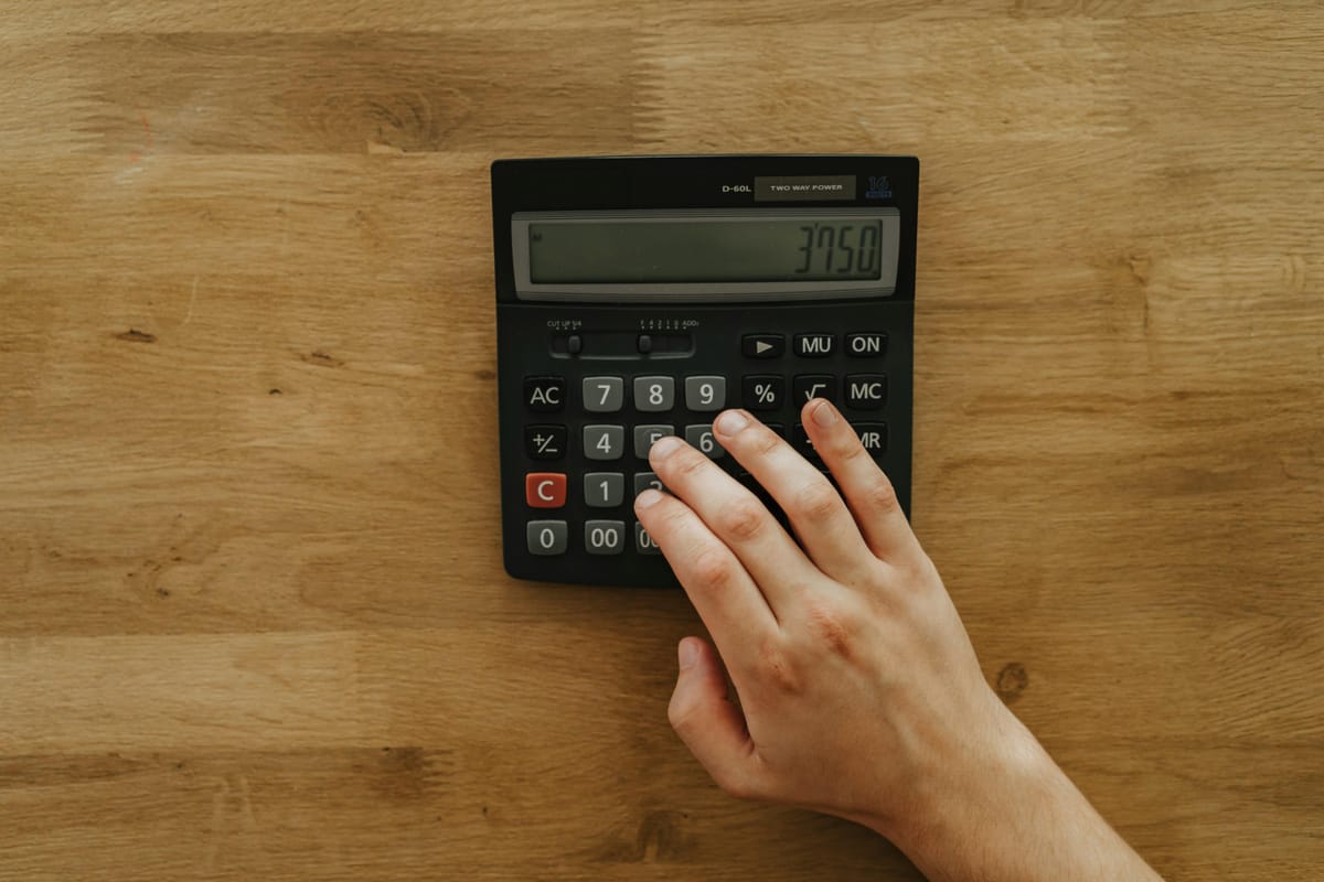 A calculator and a piece of paper on a kitchen table.