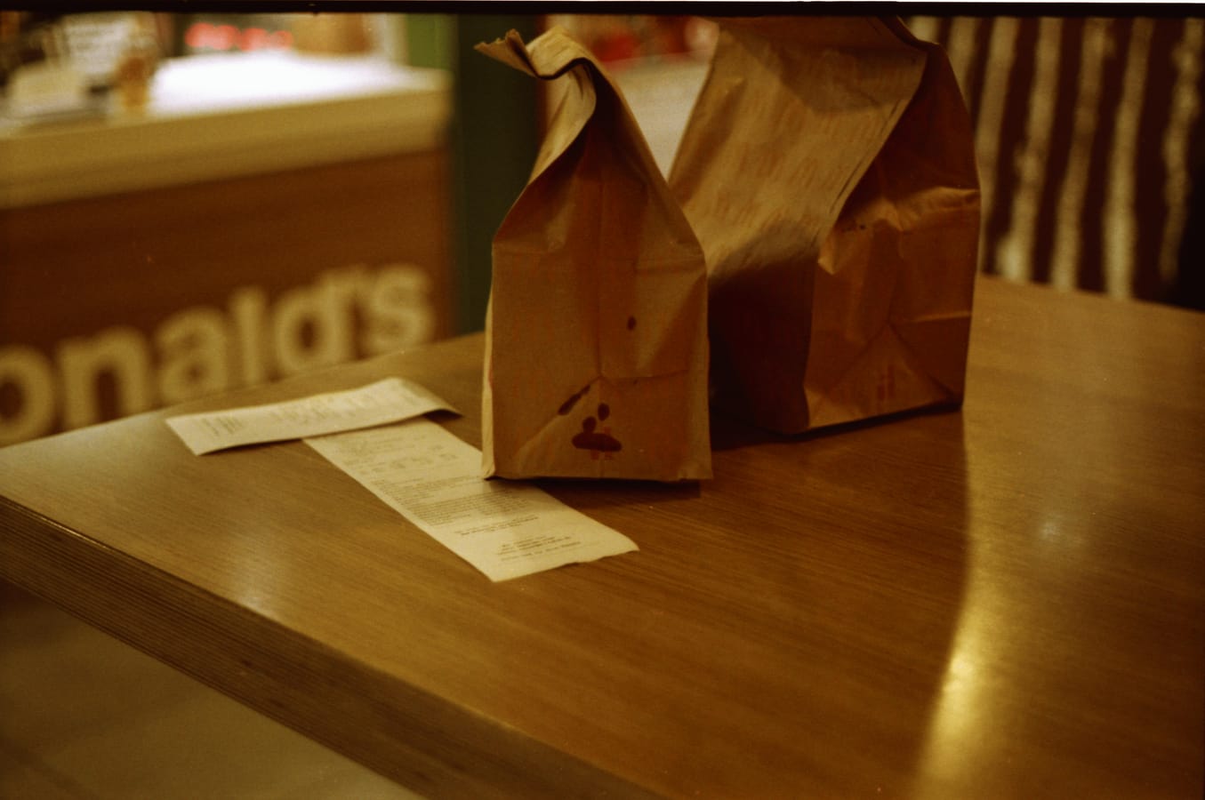 A scattered receipt, an Uber app screen, and a takeaway food container on a wooden surface.