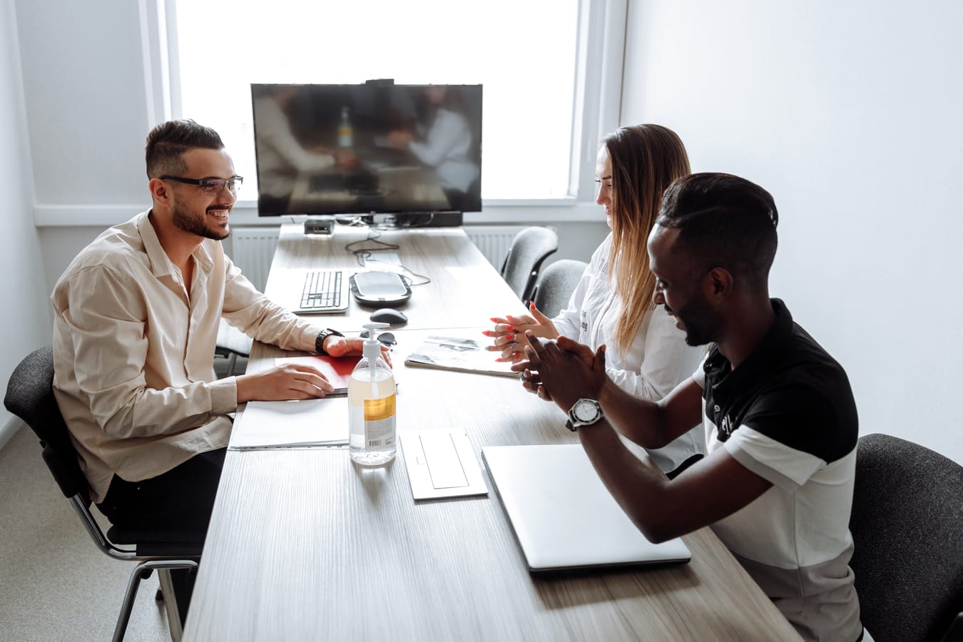 A small group of people talking around a table in a bright community room.