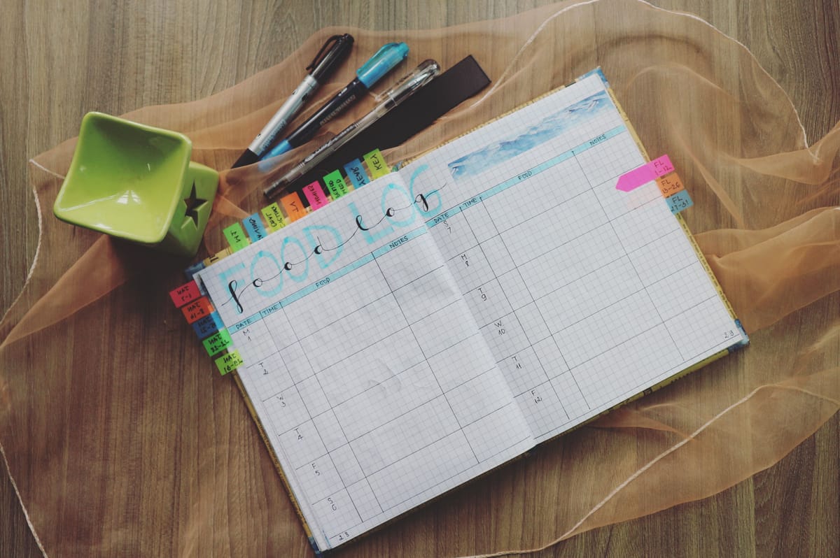 A notebook with a simple weekly log and a pen.