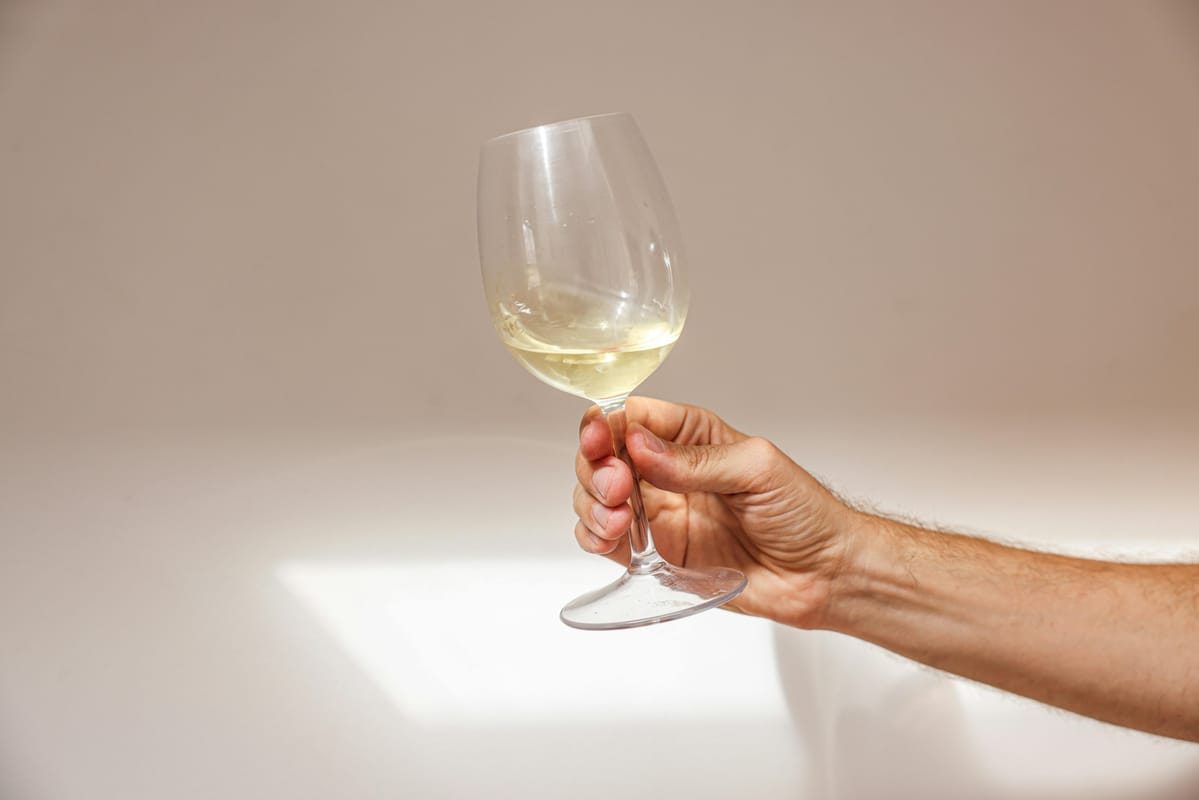 A hand holding a wine glass.