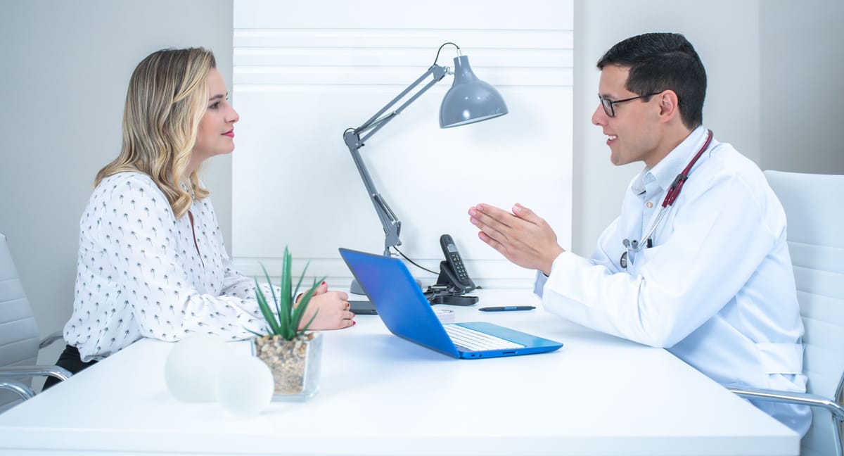 A clinician and patient talking across a desk.