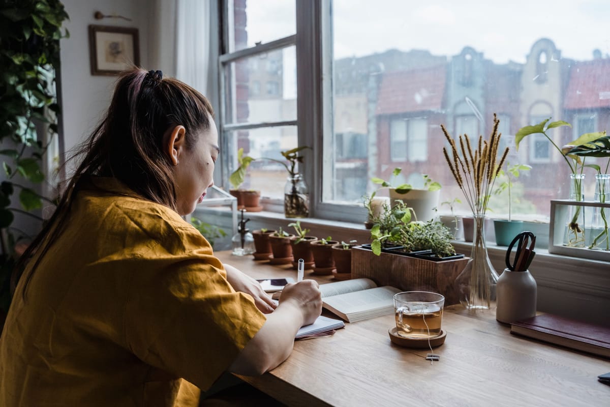 A person writing in a notebook at a table.