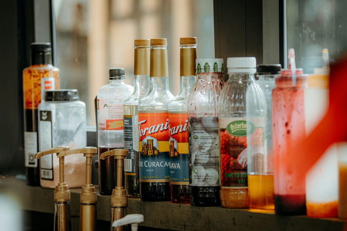 A row of electrolyte and sports drink bottles on a kitchen counter.