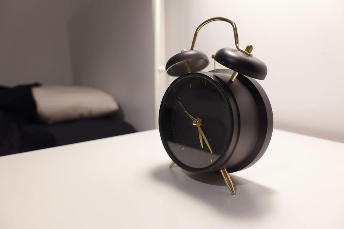 A bedside clock showing an early-morning time in dim light.