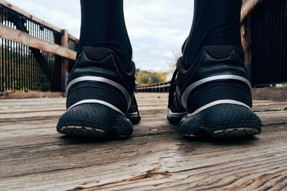 A pair of running shoes near a doorway in soft natural light.