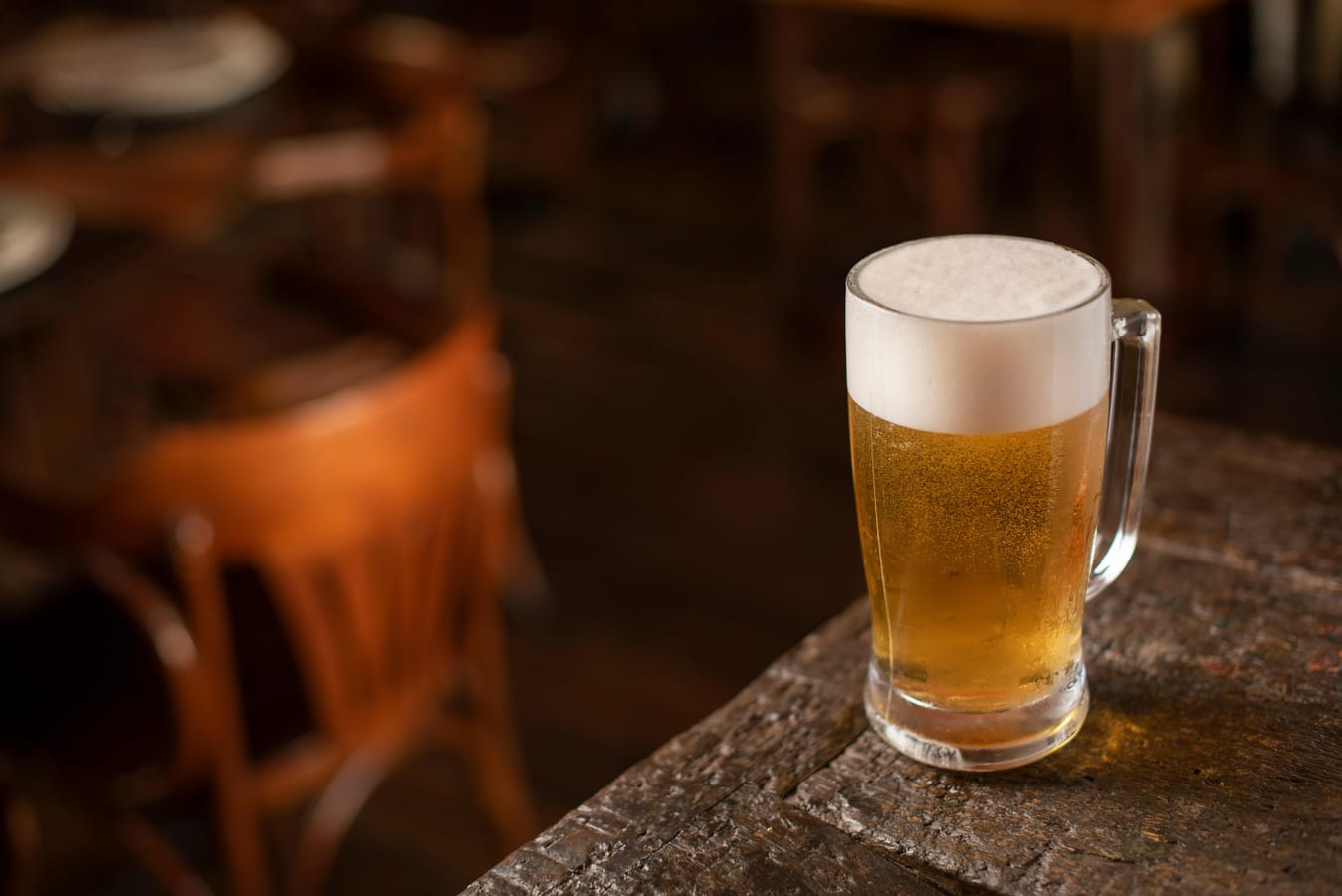An iPhone on a wooden bar table beside a half-finished pint, suggesting using a tracker mid-session.