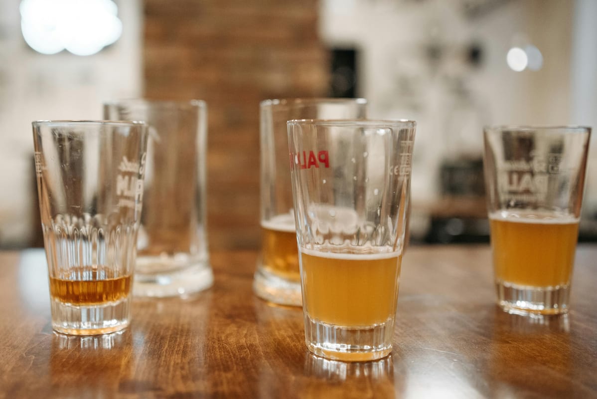 A pint of beer beside a glass of water on a wooden bar table.
