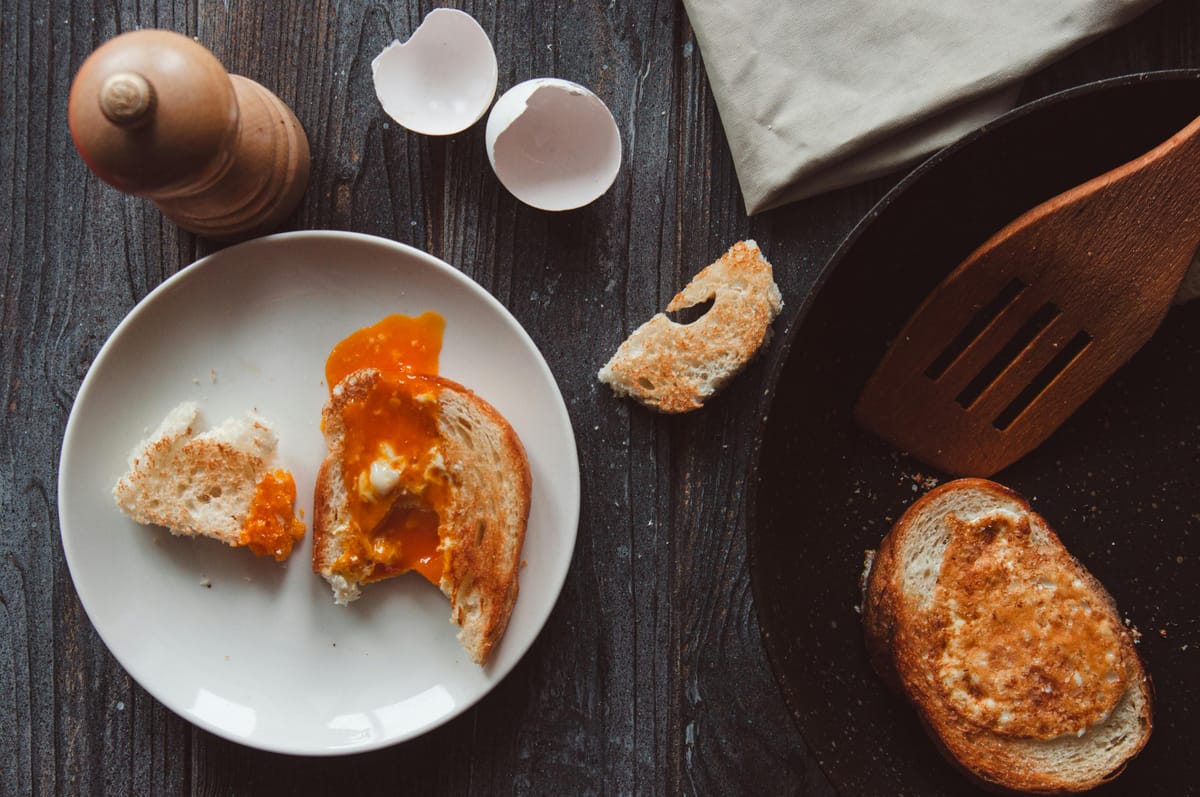 A simple breakfast of eggs and toast on a wooden table in morning light.