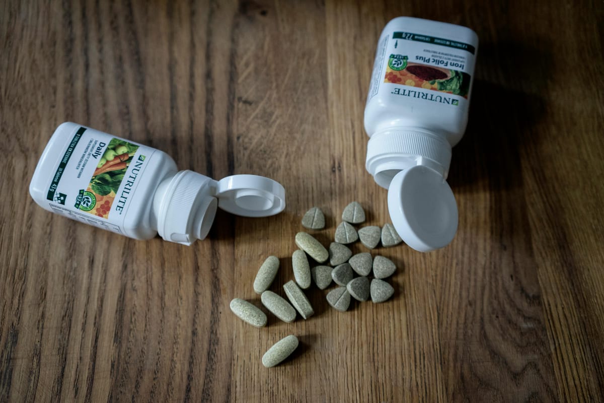 A row of small supplement bottles on a wooden table.