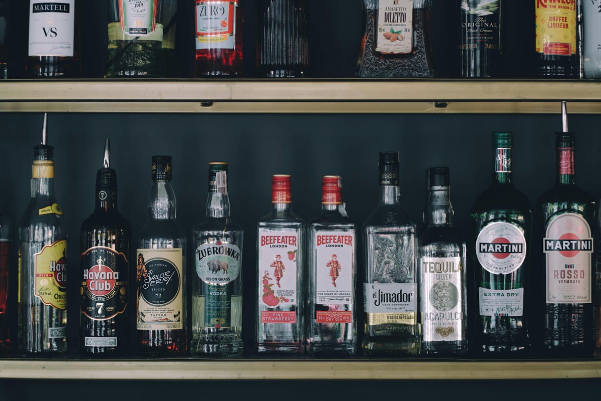 A row of clear spirit bottles on a bar shelf.