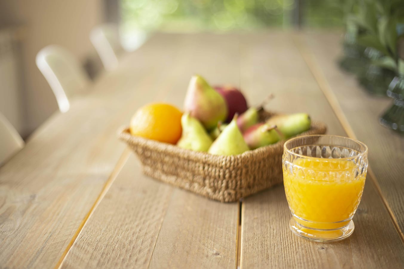 A glass of pear juice on a wooden kitchen counter in soft natural light.