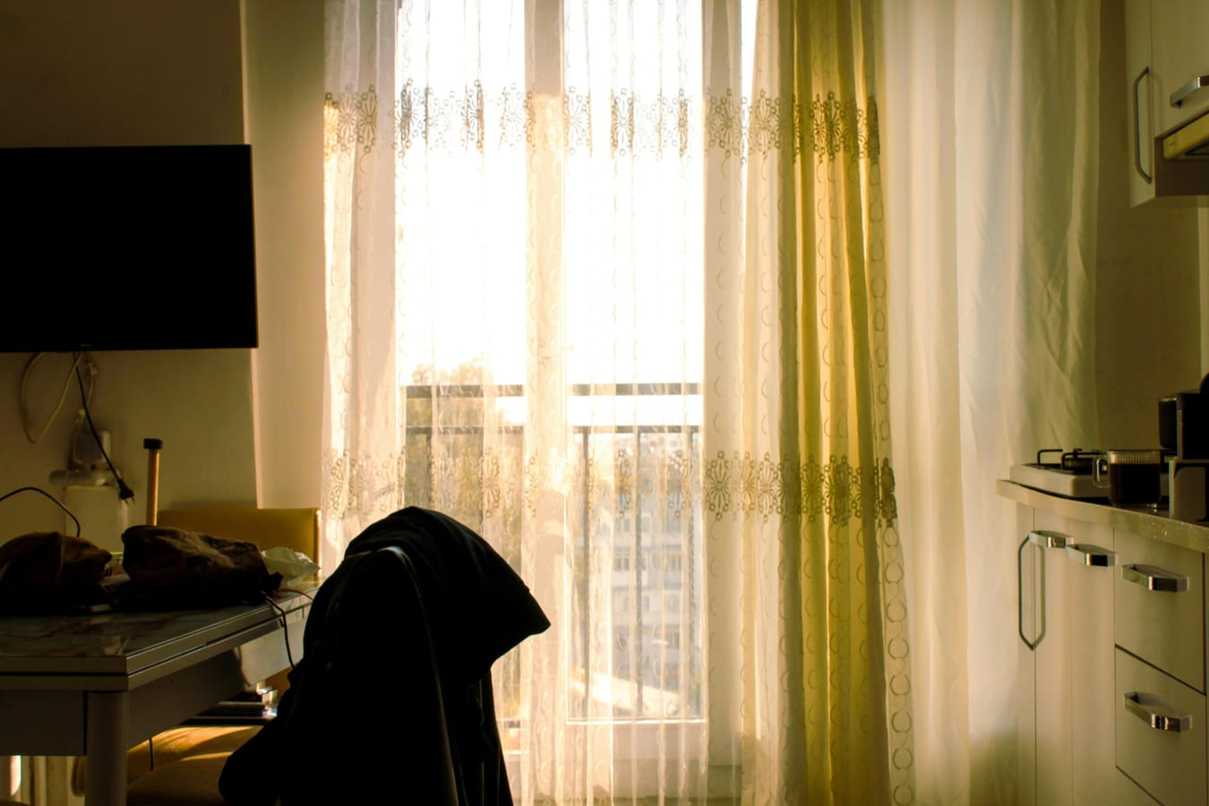 A wooden kitchen counter in soft late-afternoon light, with a partially-curtained window.
