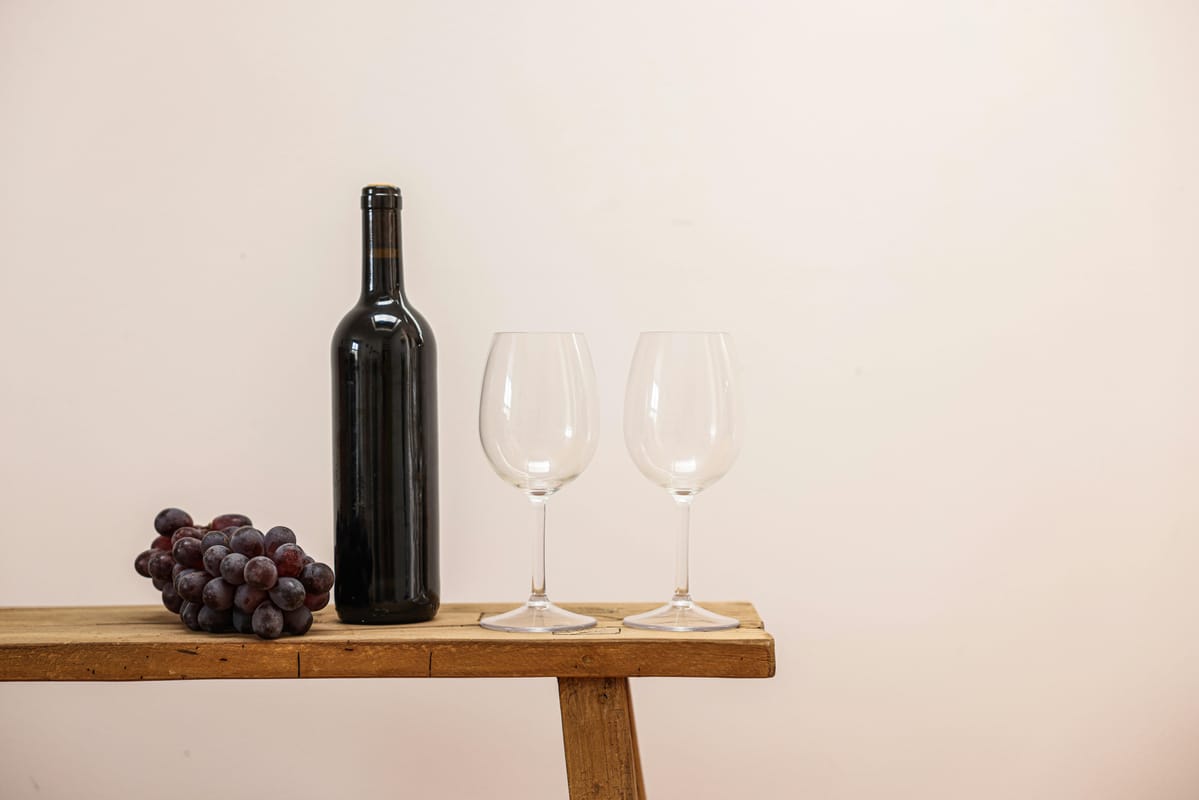 A glass of red wine with grapes on a wooden table.