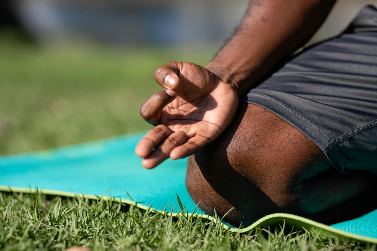 A close-up of hands resting on knees in a seated position.