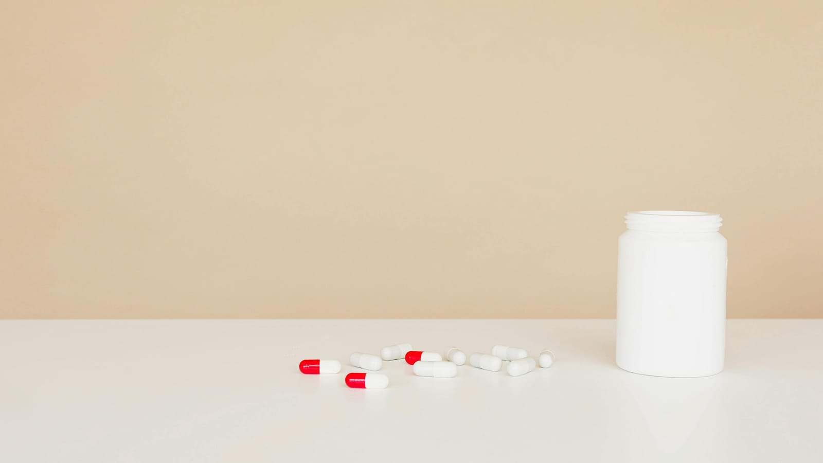 A small bottle of prescription pills on a wooden table in soft natural light.