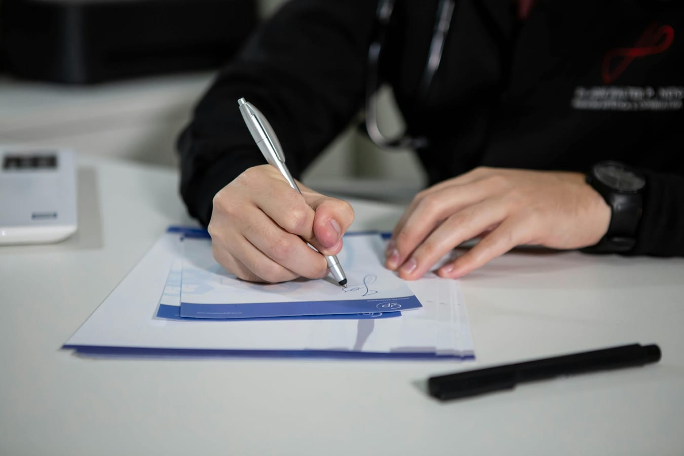 A doctor's prescription pad and a pen on a wooden desk in soft natural light.