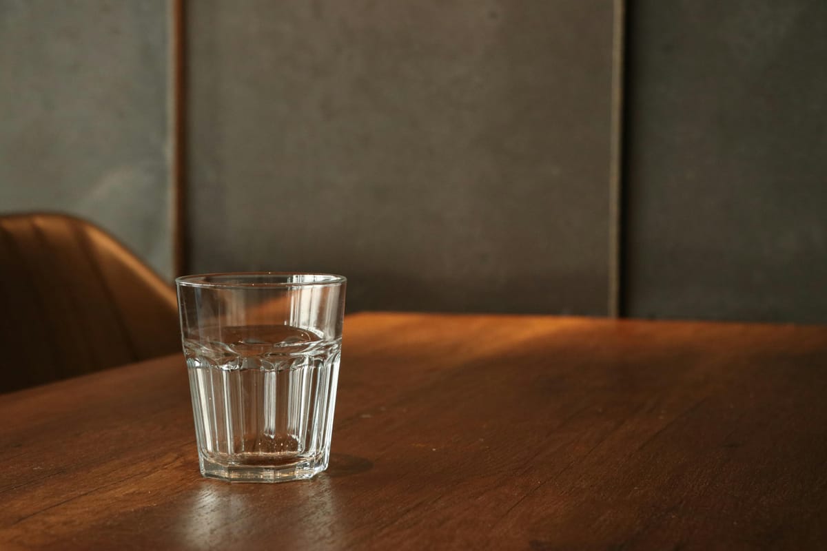 A glass of water on a wooden table in natural light.