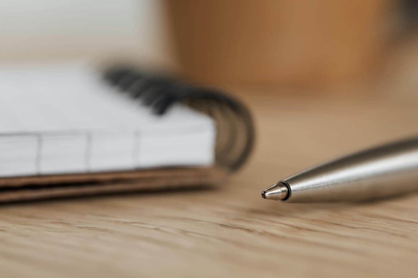 An open notebook with a pen on a wooden desk in soft natural light, suggesting careful research.