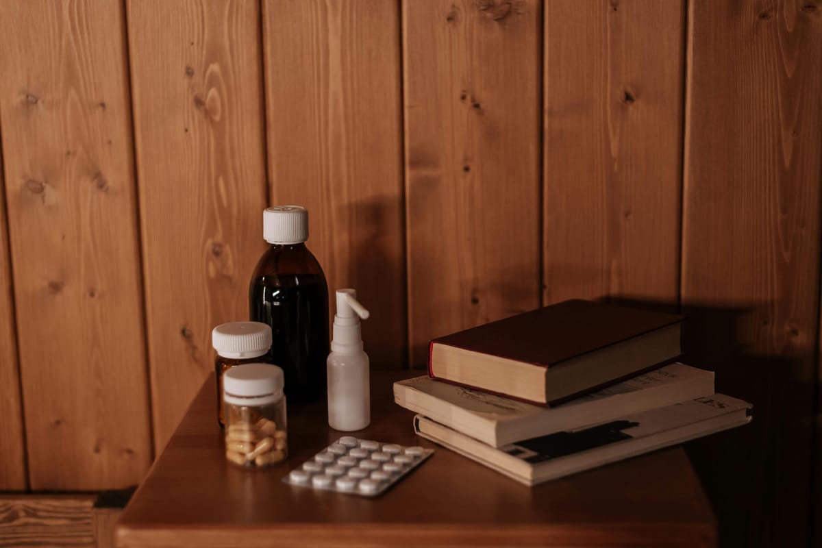 A small medication bottle on a wooden table beside an open notebook.
