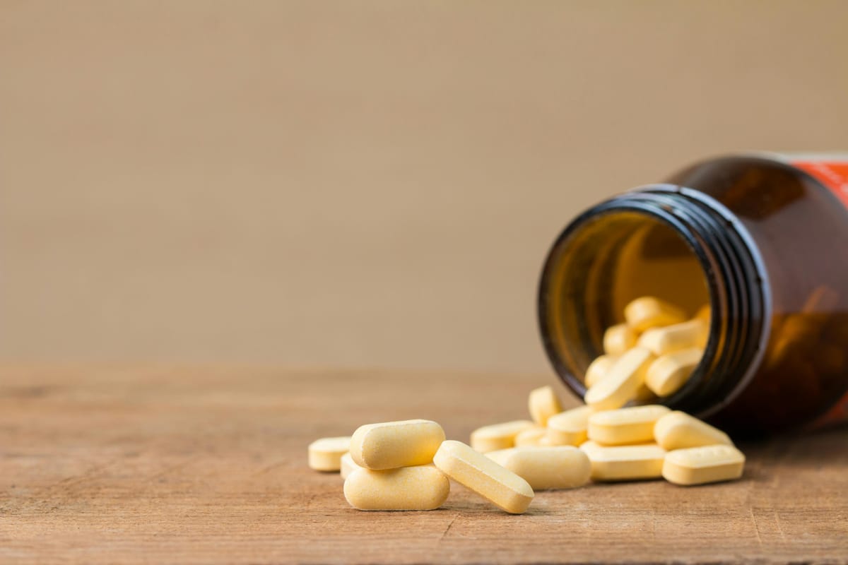 A pill bottle with a single tablet visible on a wooden surface.