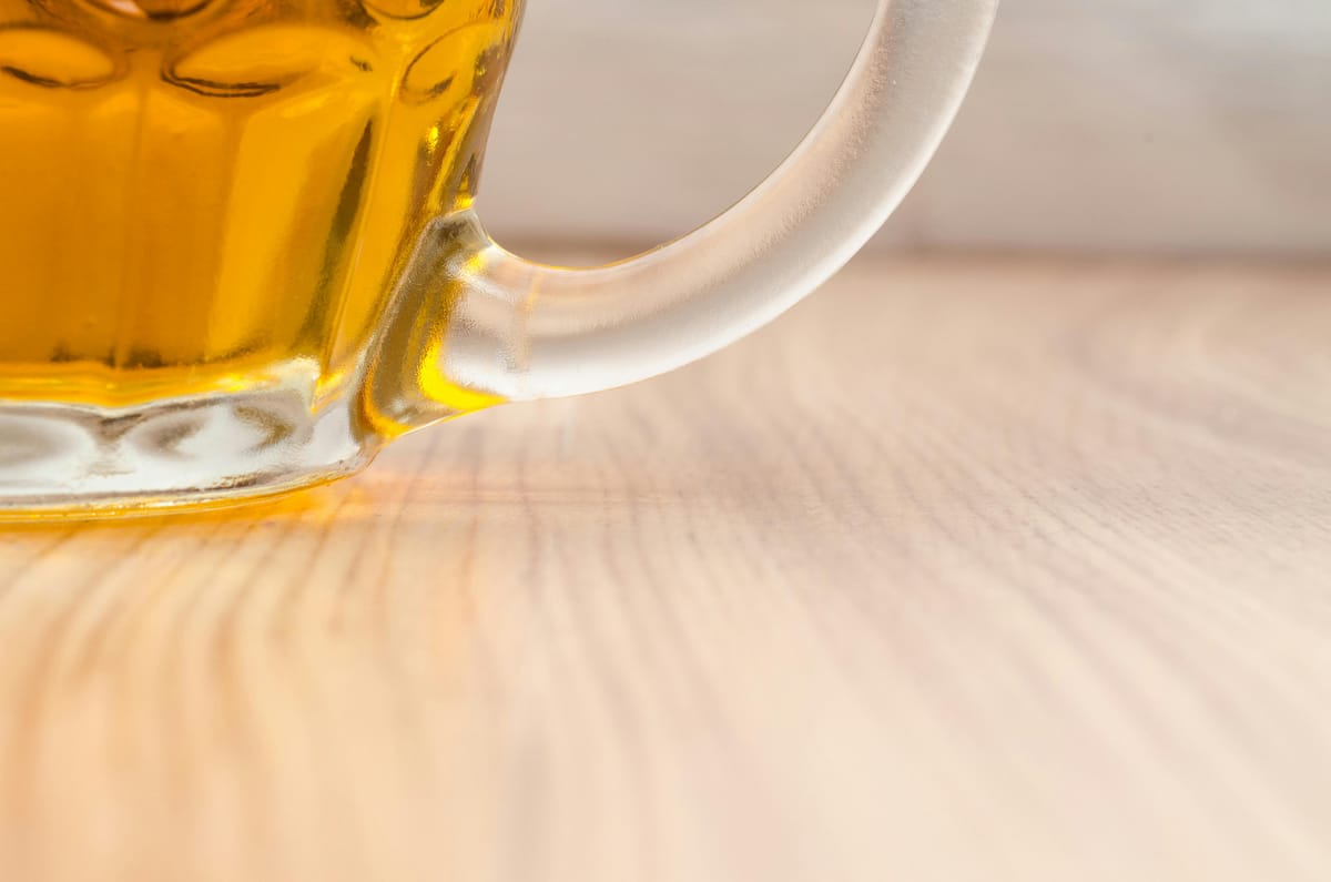 A pint of beer beside an open notebook on a wooden table.