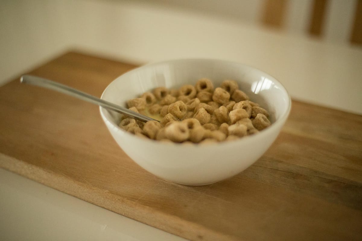 A simple breakfast with a glass of water on a wooden kitchen table in morning light.