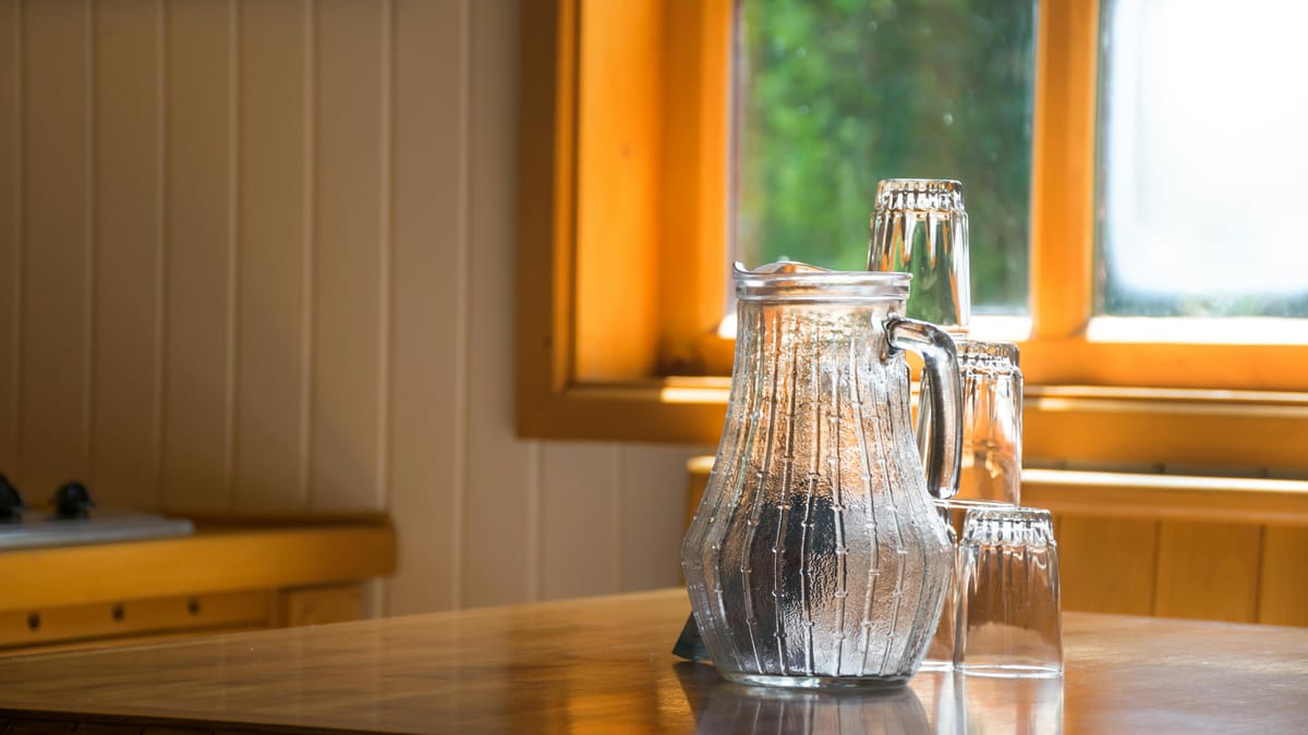 A glass of water on a wooden table in morning light.