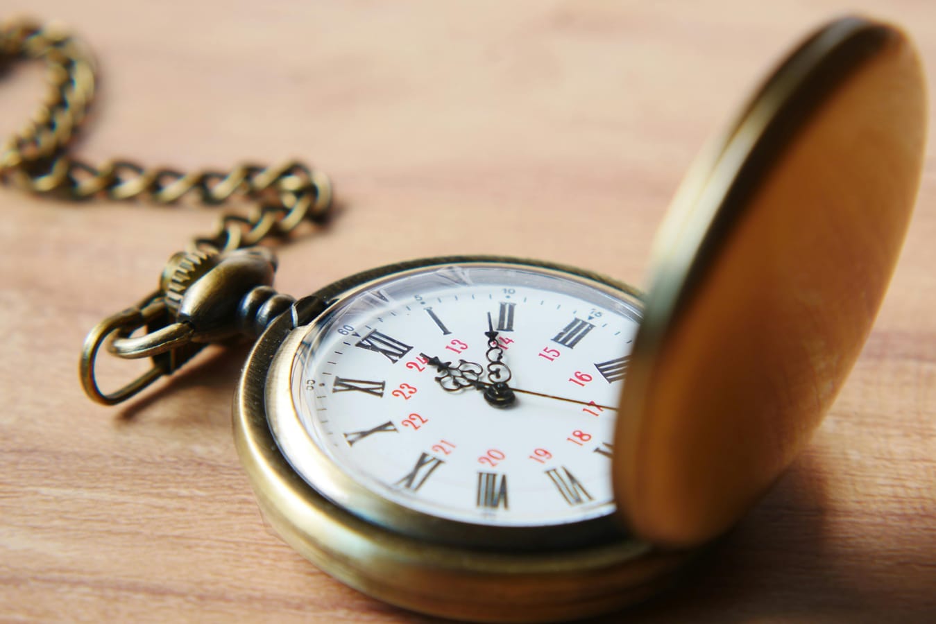 A pocket watch resting on a wooden surface, suggesting careful timing.