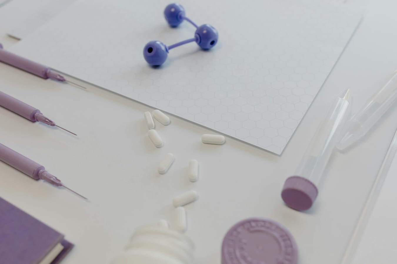 A medical syringe and a small pill bottle on a wooden surface in soft natural light, suggesting a delivery comparison.