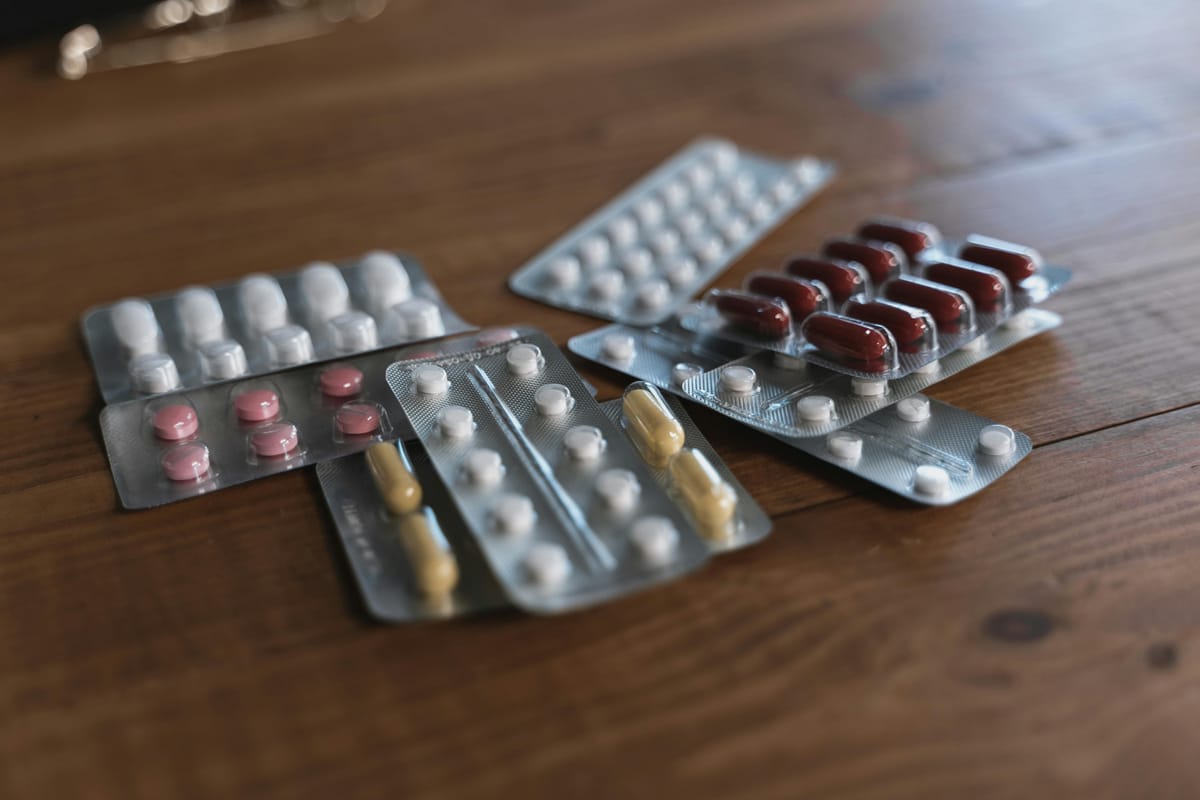 A blister pack of pills on a wooden table in morning light.