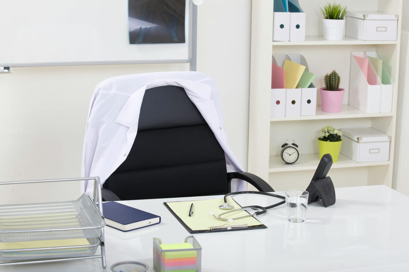 An empty doctor's consultation room with a chair and desk, in soft natural light.