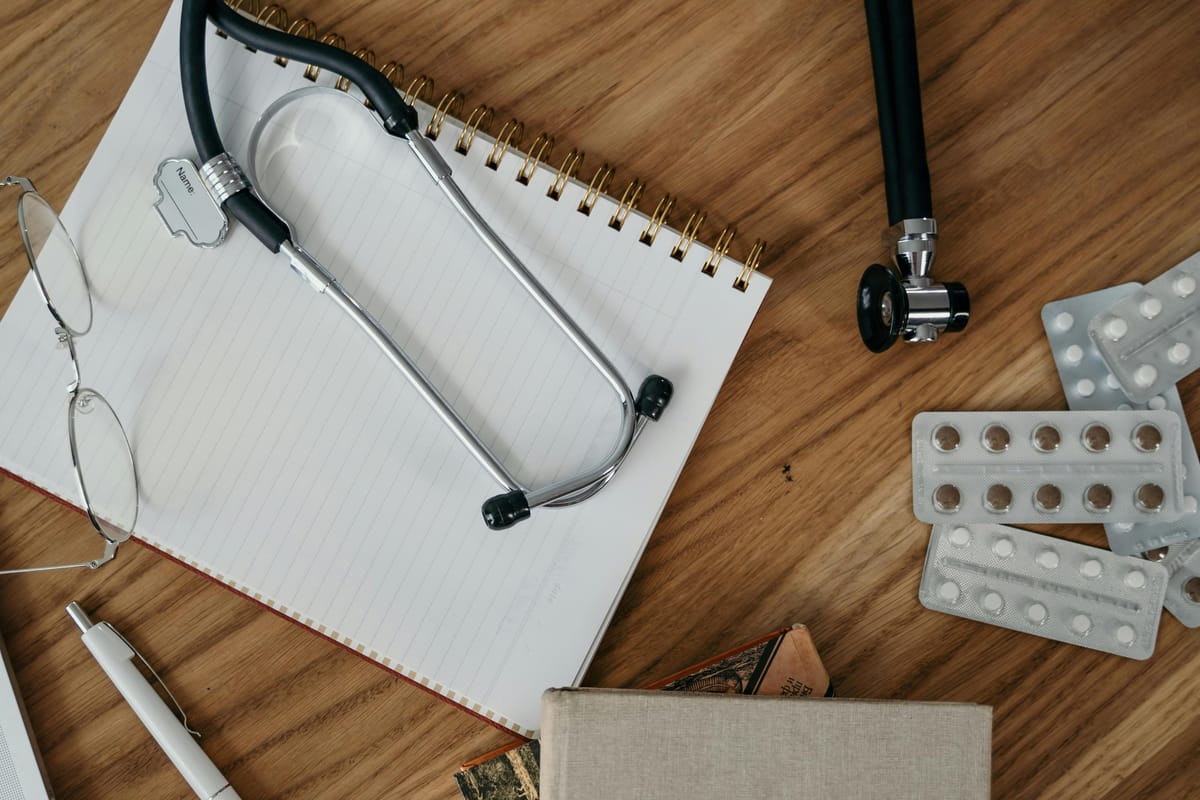 A doctor's notebook and stethoscope on a desk.