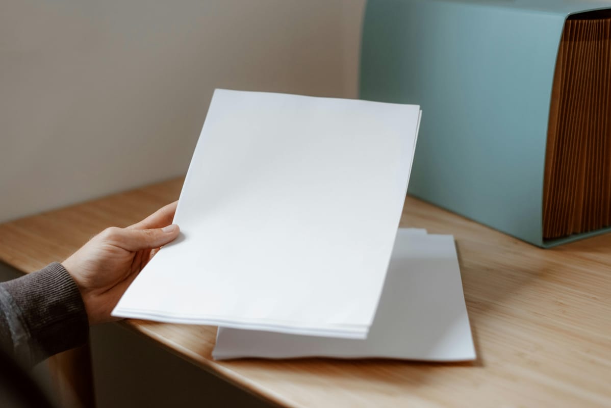 Hands holding a printed list at a desk, suggesting preparation for an appointment.