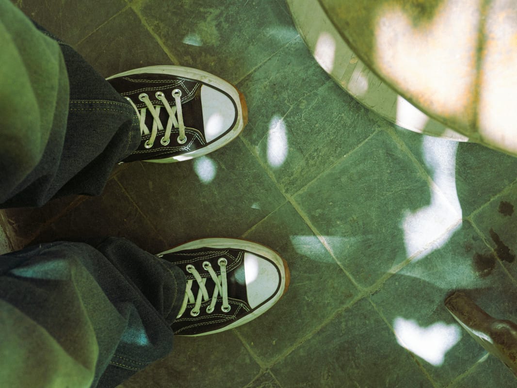 A pair of walking shoes by a doorway in morning light.