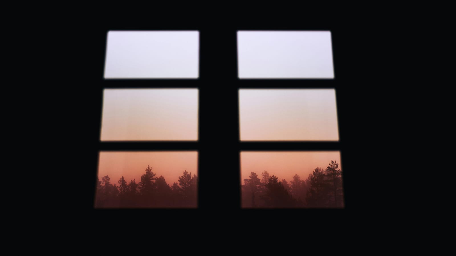 A view through a window showing a sunrise over a calm landscape, suggesting new beginnings.