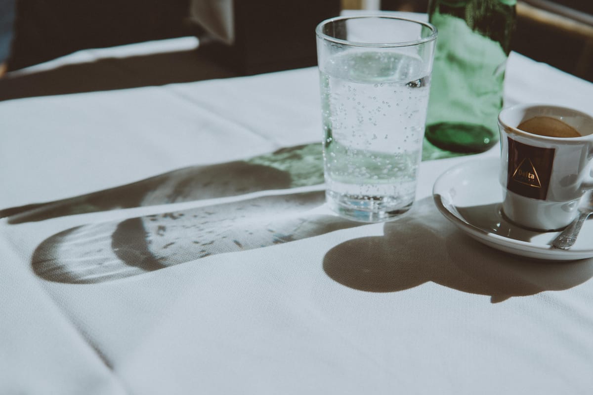 A glass of water on a sunlit table.
